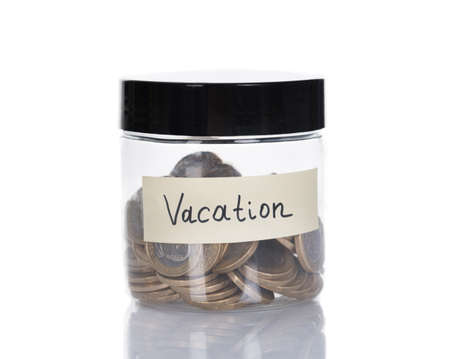 Vacation glass jar filled with coins isolated over white backgroundの写真素材