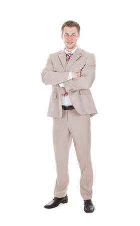 Full length portrait of handsome young businessman standing arms crossed over white backgroundの写真素材