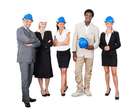 Full length portrait of multiethnic architects with hardhats standing against white backgroundの写真素材