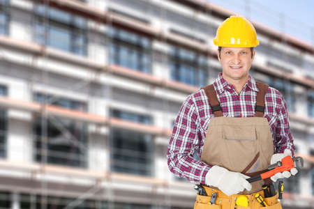 Portrait of mid adult architect holding adjustable wrench against building