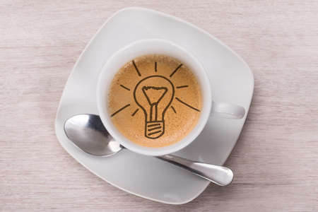 Directly above shot of coffee with light bulb on wooden tableの写真素材