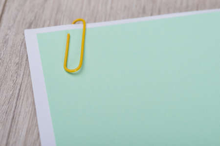 Blank green memo note with paperclip on table