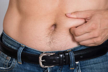 Closeup midsection of man holding fat belly