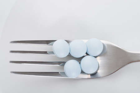 Closeup of pills on fork in plateの写真素材