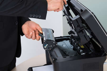 Midsection of businessman fixing cartridge in photocopy machine at office