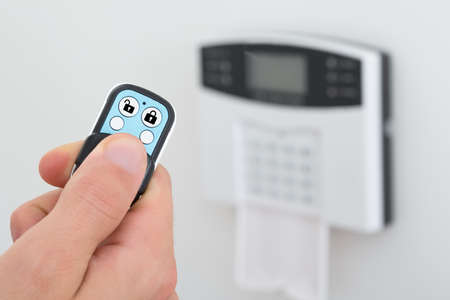 Close-up Of A Person Using Remote Control To Disarm The Security System