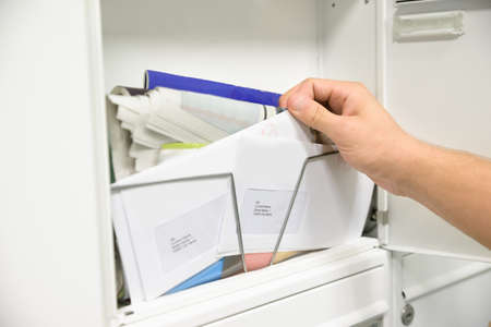 Close-up Of Man's Hand Taking Letter From Opened Mailboxの写真素材
