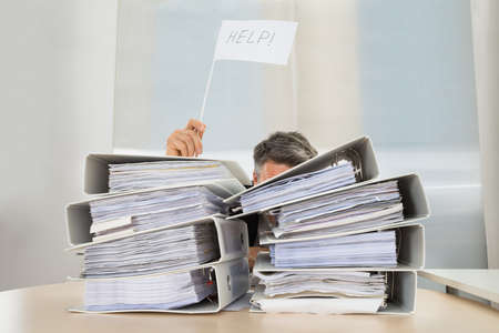 Stack Of Folders In Front Of Businessman Holding White Flag With Help Text