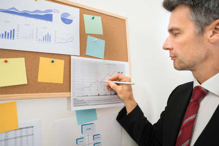 Close-up Of Businessman's Hand Drawing Graph On Paper With Penの写真素材