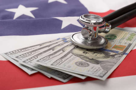 Close-up Of Stethoscope On Us Currency And American Flagの写真素材