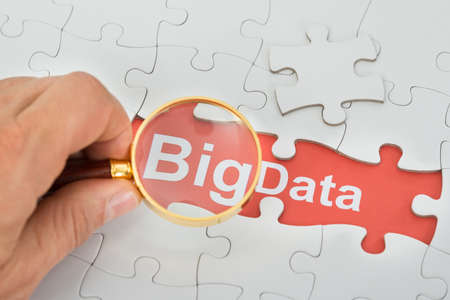 Close-up Of Person's Hand Holding Magnifying Glass Over Big Data Textの写真素材