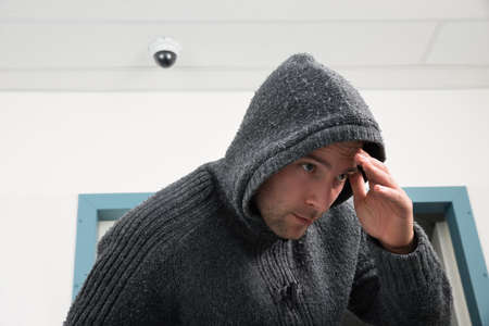 Man In Hooded Sweatshirt Trying To Hide From Security Camera