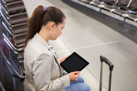 Young businesswoman using tablet computer while waiting for flight at airport lobbyの写真素材