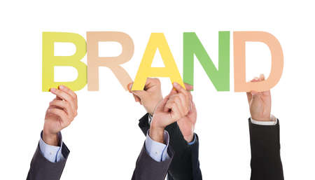 Close-up Of Businesspeople Hand Holding The Word Brand Over White Backgroundの写真素材