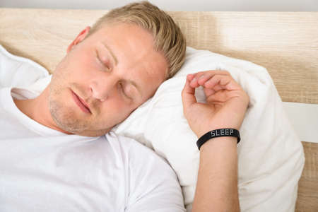 Close-up Of Young Man Sleeping Wearing Smart Wristbandの写真素材