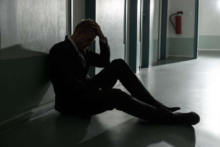 Portrait Of Unhappy Businessman Sitting On Floor In Officeの写真素材