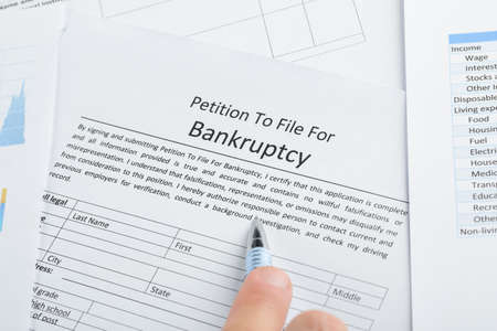 Close-up Of Hand With Pen On Bankruptcy Filing Petition Paperの写真素材