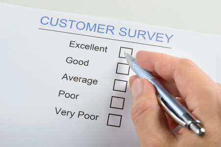 Close-up Of Person Hand Filling Customer Survey Form With Penの写真素材