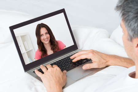 Close-up Of A Man Video Chatting With Woman At Homeの写真素材