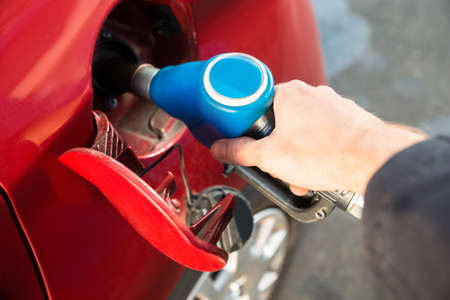 Man Refilling The Red Car With Fuel At Gas Station