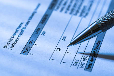 Close-up Of A Person Filling Invoice Paper With Penの写真素材