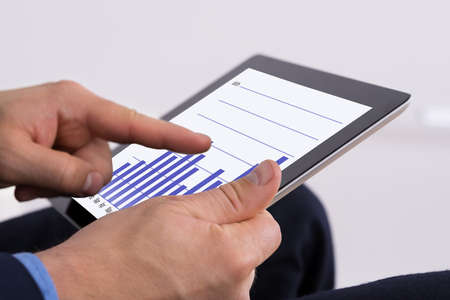 Close-up Of Businessman Holding Digital Tablet Analyzing Graph