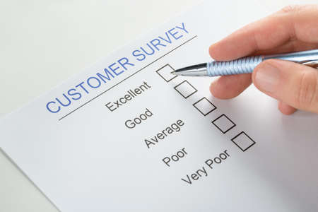 Close-up Of Person Hand With Pen Over Blank Customer Survey Formの写真素材
