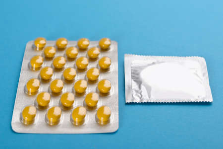 Close-up Of Condom And Birth Control Pills On Blue Backgroundの写真素材