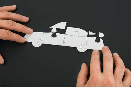 Close-up Of A Person's Hand Solving Car Jigsaw Puzzleの写真素材