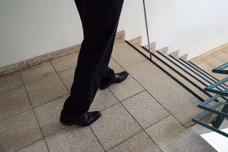Close-up Of A Blind Man Walking Near Stairway Holding Stick