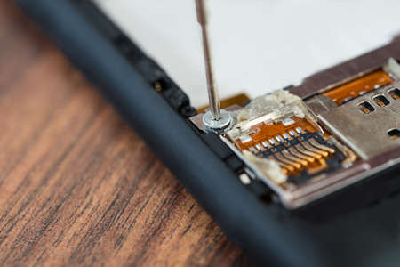 Close-up Of Technician Hand Fixing Cellphone With Screwdriverの写真素材