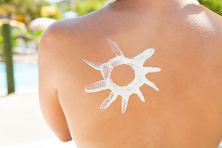 Midsection of young woman with sun shaped suntan lotion on backの写真素材