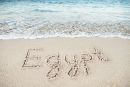 Egypt written on sand by sea at beachの写真素材