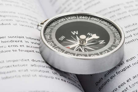 Close-up Of Compass On An Opened Book Indicating Directionの写真素材