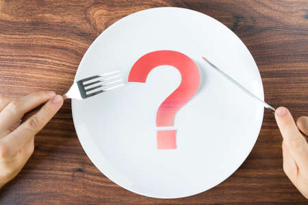 Cutlery In Hand With Red Question Mark On White Plateの写真素材