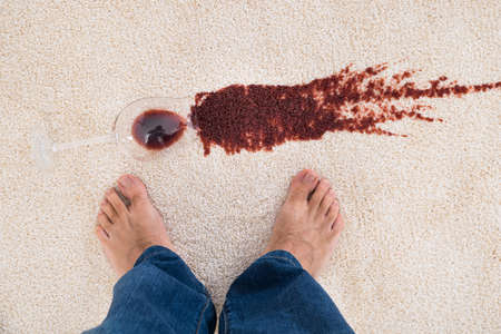 Close-up Of A Person's Feet Standing Near Red Wine Spilled On Carpetの写真素材