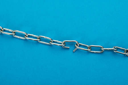 Close-up Of Broken Silver Chain Over Blue Backgroundの写真素材