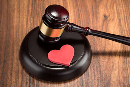 Close-up Of Wooden Gavel And Red Heart On Tableの写真素材