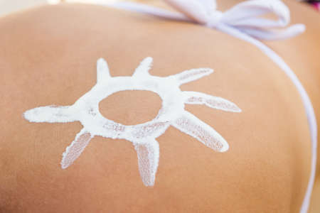 Midsection of young woman with sun shaped suntan lotion on back
