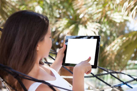 Side view of young woman using digital tablet at beachの写真素材