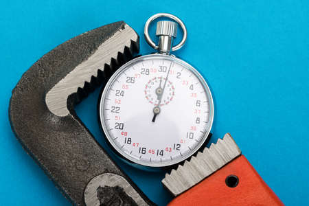 Close-up Of Adjustable Wrench And Stopwatch Over Blue Background