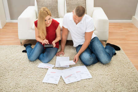 Young Couple Sitting and Calculating Bills At Home