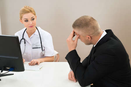Male Patient With Young Female Doctor At Clinicの写真素材