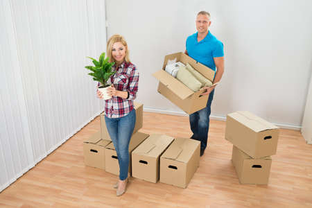 Portrait Of Happy Young Couple Moving Boxes In New Home