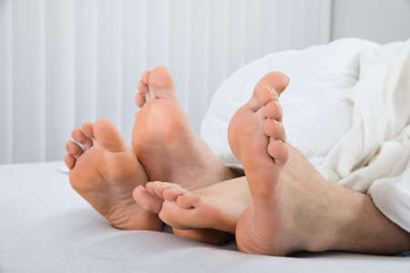 Close-up Of Four Feet In White Bed