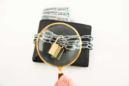 Close-up Of Person Hand Examining Money Wallet With Magnifying Glass