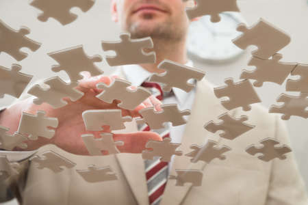 Businessman Separating Jigsaw Puzzle On Glass Tableの写真素材