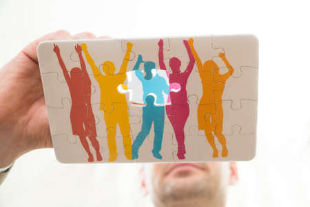 Close-up Of Person Hand Making Colorful Human Figure Of Puzzle