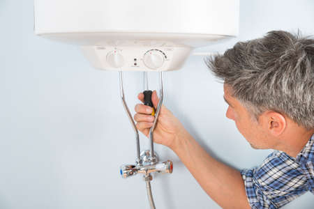 Close-up Of Mid-adult Male Plumber Repairing Water Heaterの写真素材