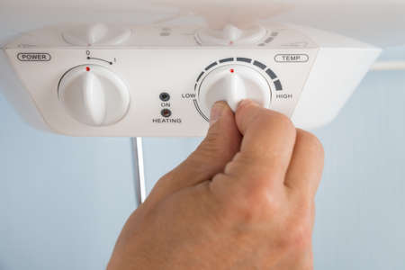 Close-up Of A Person's Hand Adjusting Temperature Of Electric Boilerの写真素材